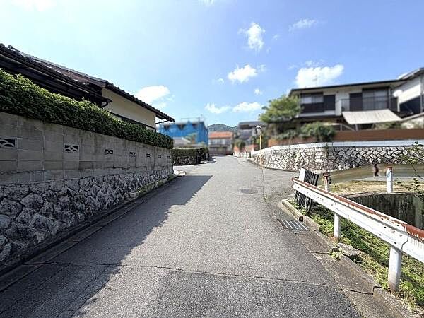 西側幅員約6.2mの前面道路。奥には山並みが望め、自然豊かな落ち着いた住宅街であることがわかります。緑が多く爽やかな景観も特徴です。
