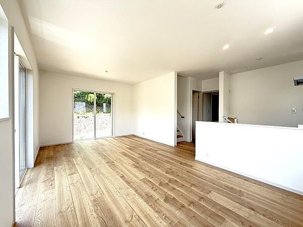 窓からの採光で明るいリビングルーム。無垢感のある明るいフローリングと白い壁・天井が相まって、LDK全体に一体感と広がりをもたらす上質なリビング空間。