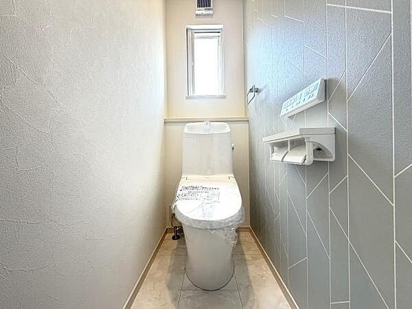 落ち着いた雰囲気のトイレ空間です。窓があるため換気がしやすく清潔感のある内装が魅力です。ペーパーホルダーや操作パネルも使いやすい位置に配置されています。