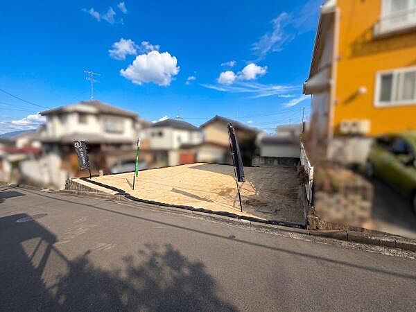 開放感のある現地土地写真。周辺には住宅が整然と並び、静かで落ち着いた雰囲気。青空が広がる落ち着いた環境です。前面道路も見通しが良く日当たりも確保されています。敷地内の様子が一目で分かる写真です。