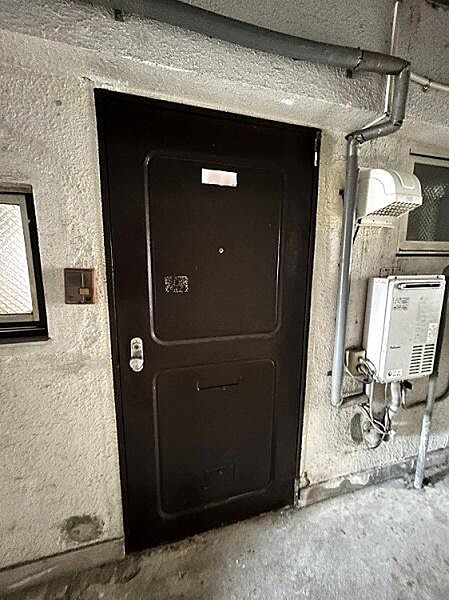 無駄のないシンプルな玄関扉が設置されています。周囲にはガス設備やインターホンが配置されています。玄関ドア横に換気用の窓も設けられています。
