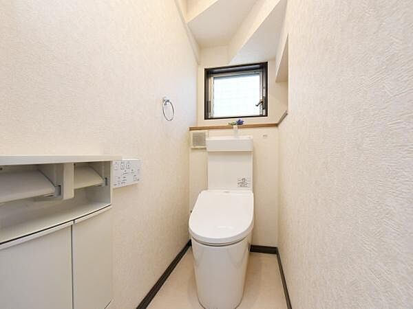 タンクレスタイプのウォシュレット付きトイレを採用。操作パネルは壁付けタイプでスマートな印象です。トイレ上部にはタンク手洗い器を設置。収納キャビネットも備わり、トイレ用品の収納に困りません。
