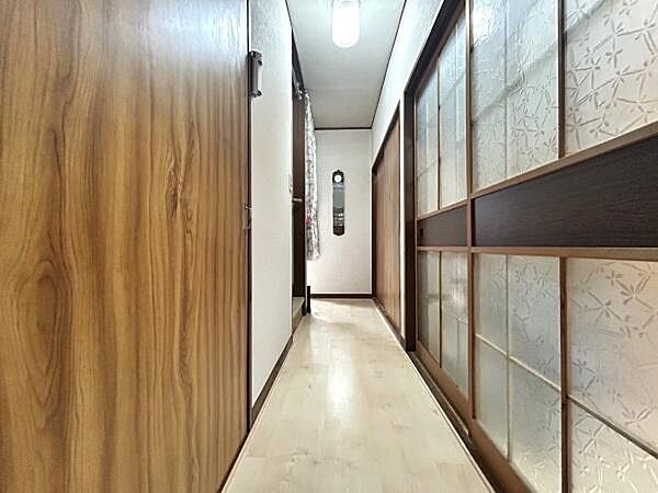 木目調の扉と和の引き戸が調和した落ち着きのある廊下です。ガラスの模様入り引き戸が奥行きを感じさせ明るい雰囲気を演出しています。天井の照明が淡い光を広げすっきりとした印象を与える空間です。