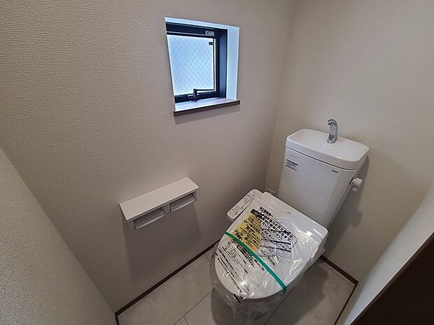ウォシュレット機能付きのトイレ。換気のしやすい窓付きで、収納もあり実用性も兼ね備えた造り。