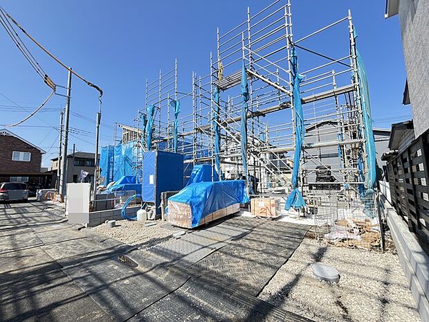 青いシートに覆われた未来の住まい、その骨格が形作られ、これから始まる新しい暮らしの予感が、澄み渡る青空の下に広がっています 