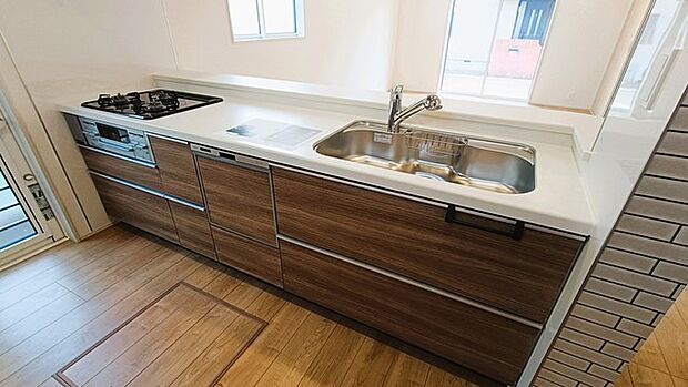 木目調の扉と白いカウンタートップが調和する、洗練されたキッチン空間。