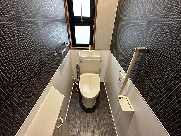【2階トイレ】快適に使用できる温水洗浄便座付トイレです。ダークカラーがシックな雰囲気を演出します。換気窓が備わっており、いつでも新鮮な空気を取り込めます。トイレは1階と2階にあります。 