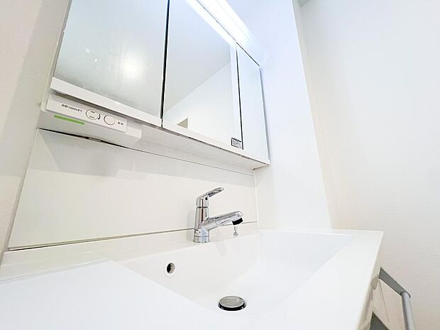 《洗面台》シャワー機能付きの洗面台です。3面鏡内や洗面台下部にも収納スペースが備わっており、消耗品の保管に便利なつくりとなっております。