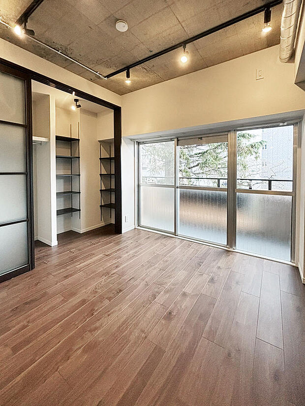 洋室 約7.4帖｜モダンな印象のコンクリートの天井と、温かい印象のフローリングとのコントラストは、どんな家具にも合わせやすく住む人の個性を引き出すデザインです。