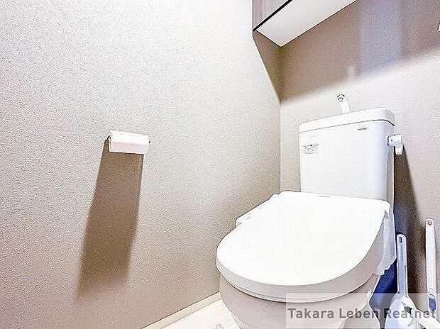 ウォシュレット機能付きのトイレ。ペーパーホルダーやタオル掛けは標準装備しています。また、上部には吊戸棚があるので、トイレットペーパーのストックや清掃道具等を収納するのに便利です。