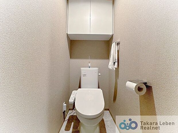 ウォシュレット機能付きのトイレ。上部には吊戸棚があるので、トイレットペーパーのストックや清掃道具等を収納するのに便利です。