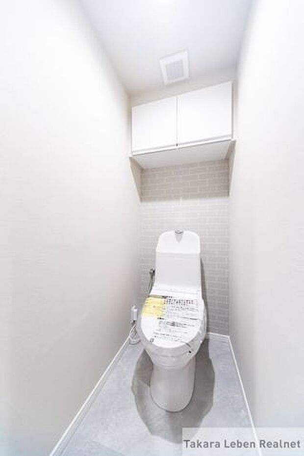 白を基調に清潔感のあるトイレ。トイレットペーパーホルダーとタオル掛けは標準で実装してます。上部に吊戸棚があり、掃除用具などの収納場所に困りません。