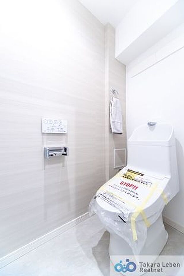 白を基調に清潔感のあるウォシュレット機能付きのトイレ。トイレットペーパーホルダーとタオル掛けは標準で実装してます。