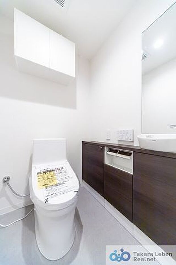 白を基調に清潔感のあるトイレ。トイレットペーパーホルダーとタオル掛けは標準で実装してます。上部に吊戸棚があり、掃除用具などの収納場所に困りません。カウンターもあるので、お洒落な空間に彩る事も出来ます。
