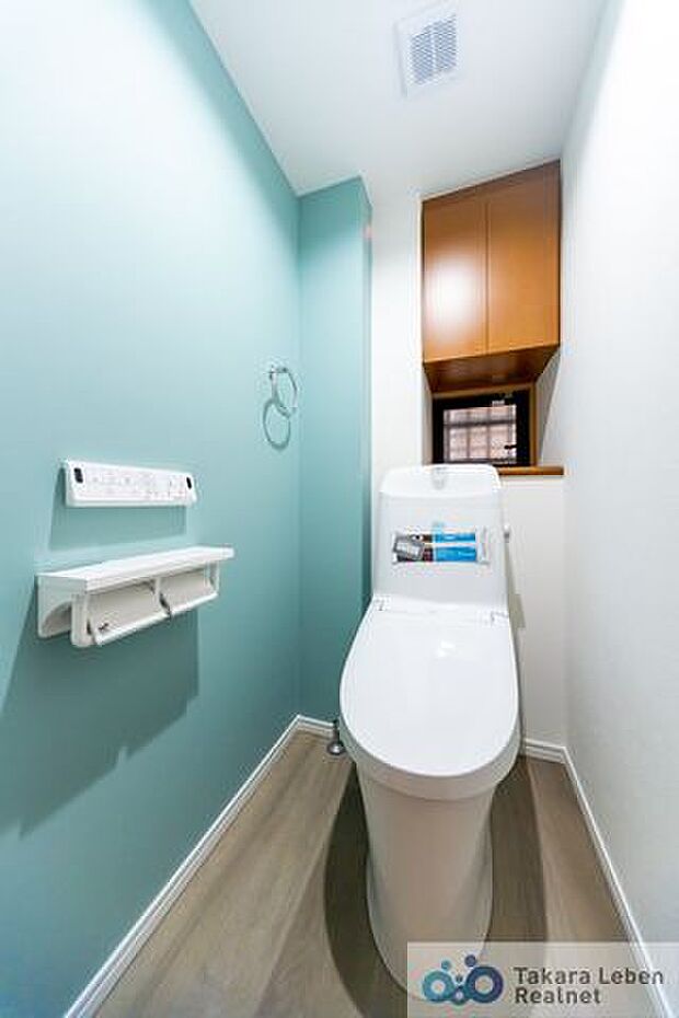 爽やかなアクセントクロスの吊戸棚付きトイレ。温水洗浄リモコンは操作しやすい壁掛けタイプ。ペーパーホルダーには2ロール設置可能です。