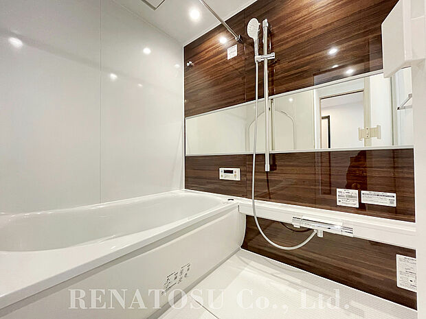 【浴室】木目調のアクセントパネルが高級感あるシステムバスルーム。ワイドな鏡が奥行を感じさせてくれます。設備として浴室暖房乾燥機付きです。