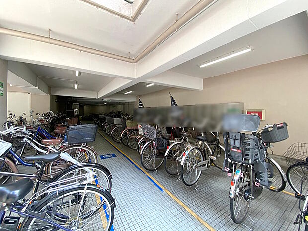 【駐輪場】屋内にある駐輪場は雨の日でも乗り降りしやすく助かります。整理整頓されていて自転車の出し入れもしやすいですね。空き状況や月額使用料については、都度確認が必要なためお気軽にお尋ねください。