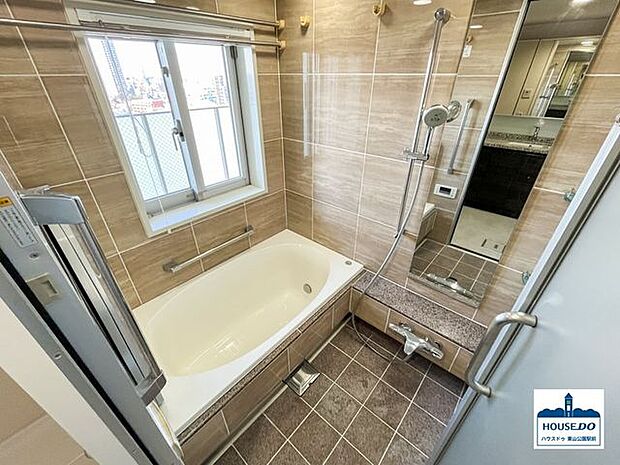 窓＆木目調タイルで穏やかで明るい内装の浴室です。浴室鏡は使い勝手の良い縦向きで設置されています