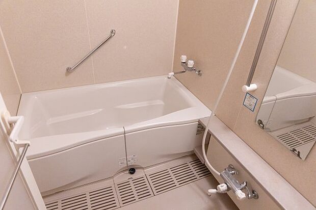 白色で統一されたきれいで清潔感のある浴室です。手すりや鏡、タオル掛けなど、必要なものがそろっており、浴槽につかれば一日の疲れも吹き飛びそうです。