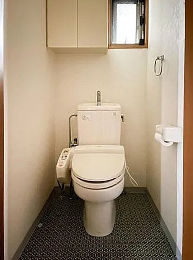 【トイレ】一年を通して快適に使用できる温水洗浄便座付トイレです。自然換気に役立つ小窓が配されています。トイレットペーパーなど収納できる上吊り棚が備わっています。