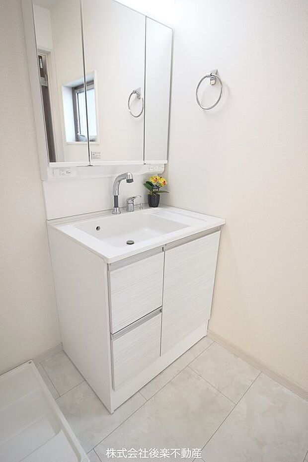 白を基調としたデザインの三面鏡化粧台。洗面所には洗濯機置き場あり。